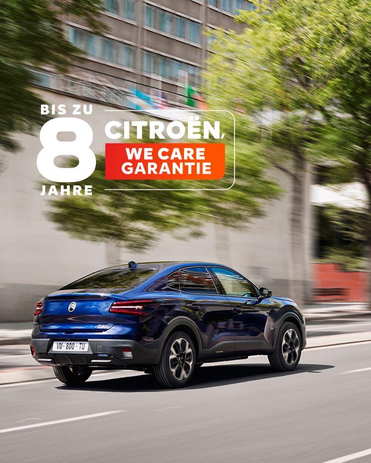 Der neue Citroën ë-C4 X in blau fährt durch eine Stadt. Ansicht von schräg hinten.