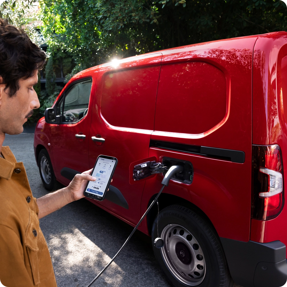 Person charging a red Citroën van, highlighting connected services and electrified mobility.