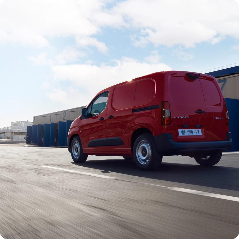 Rear three‑quarter view of a Citroën ë‑Berlingo Van driving on the road, showing efficient electric design, freedom of movement and confident presence.