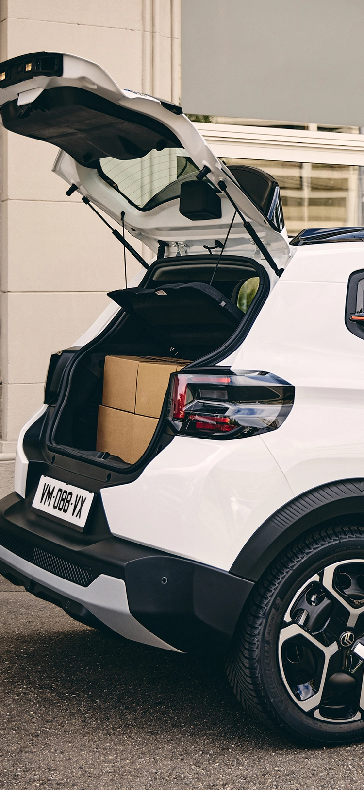 Seitliche Dreiviertel-Heckansicht des Citroën ë-C3 Van mit geöffnetem Ladebereich, die Zugänglichkeit und Beladepraktikabilität hervorhebt.