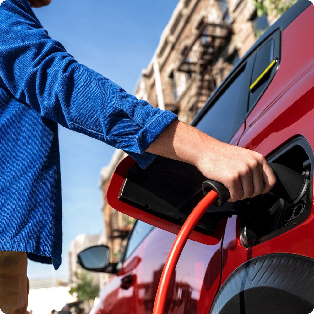 Nahaufnahme des Citroën ë-C3 Van Ladeanschlusses mit angeschlossenem Ladekabel, die komfortables elektrisches Laden und emissionsfreie Mobilität hervorhebt.