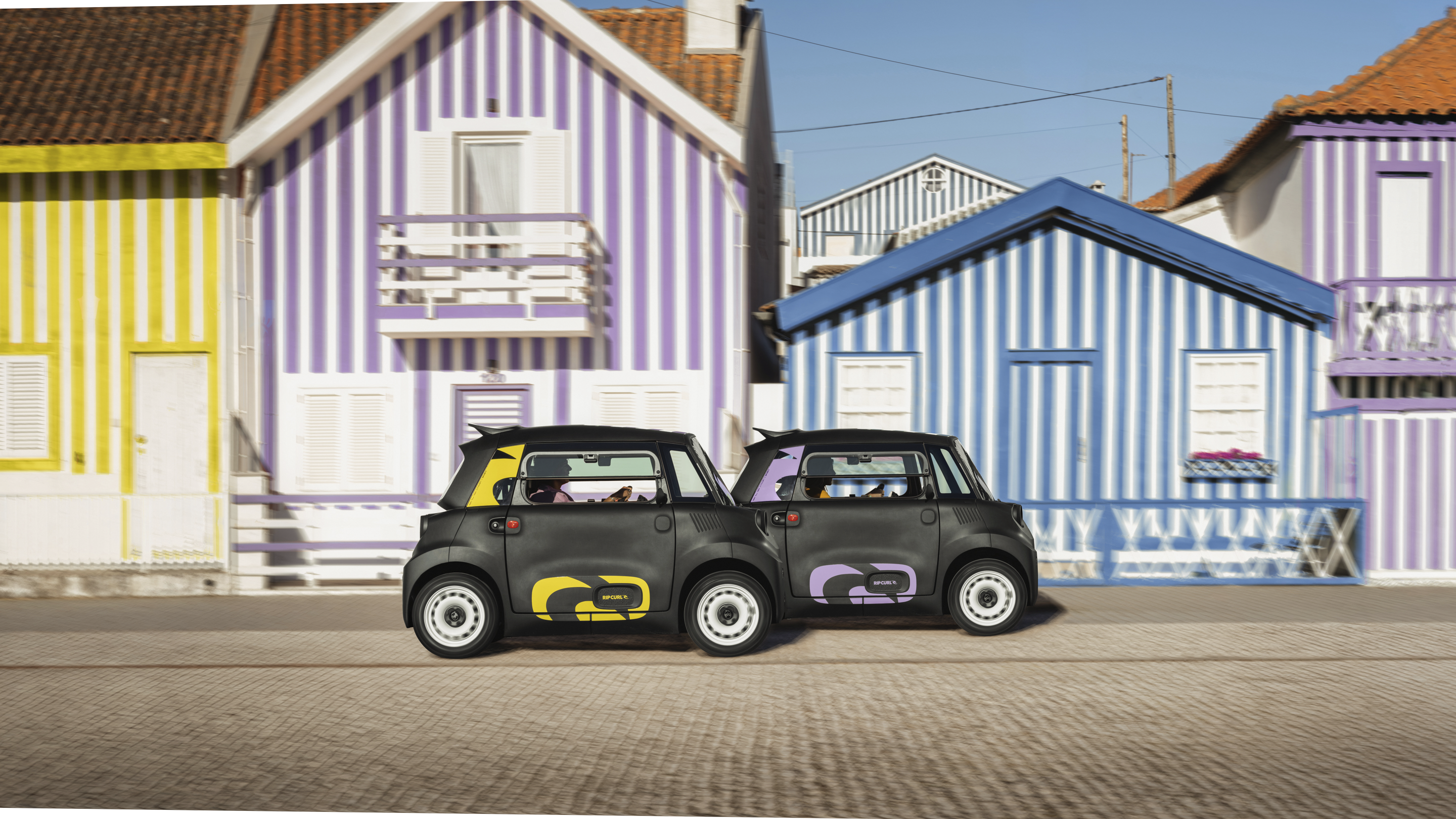 Seitenansicht auf der Straße des Citroën Ami x Rip Curl Elektro ohne Führerschein, Citroën Ami Alltagsfreiheit für urbanes Elektroauto.