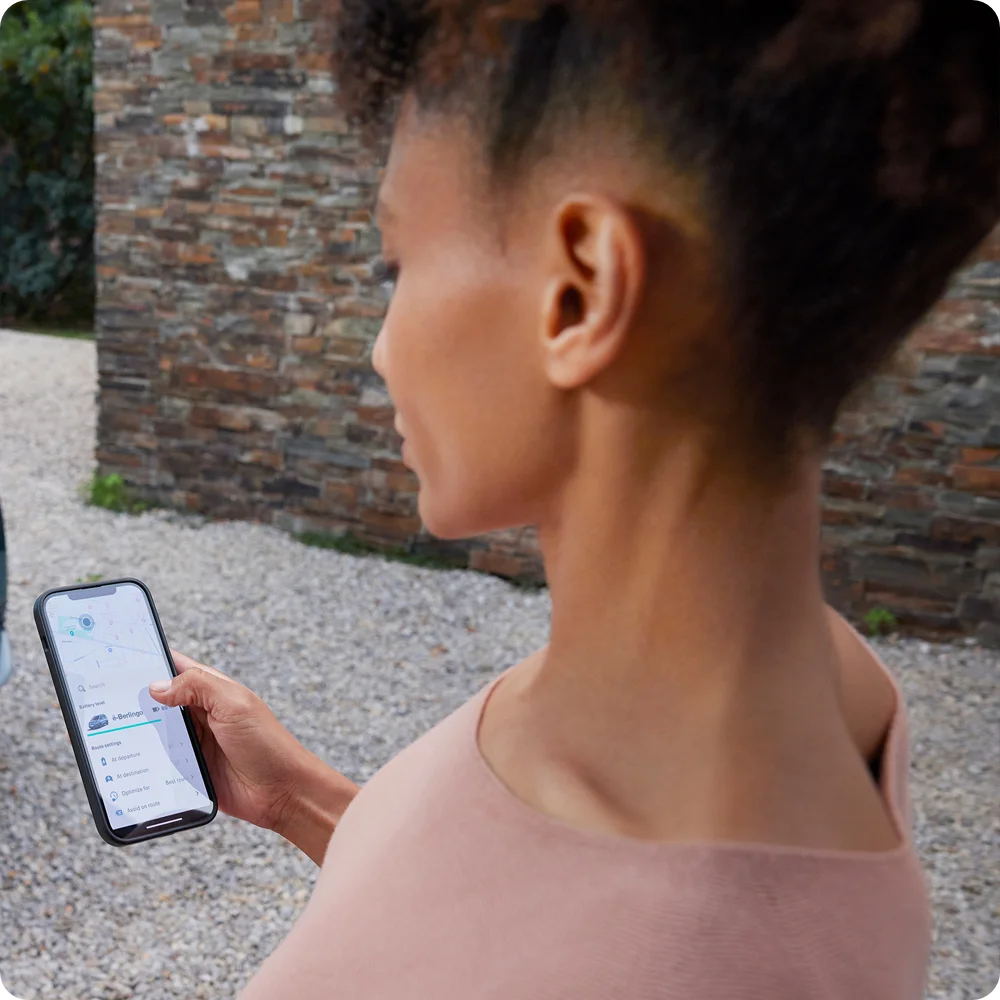 Person mit Smartphone und Free2Move Charge App, die nahtlose Routenplanung und Ladestationsführung für den Citroën ë-C3 Van hervorhebt.