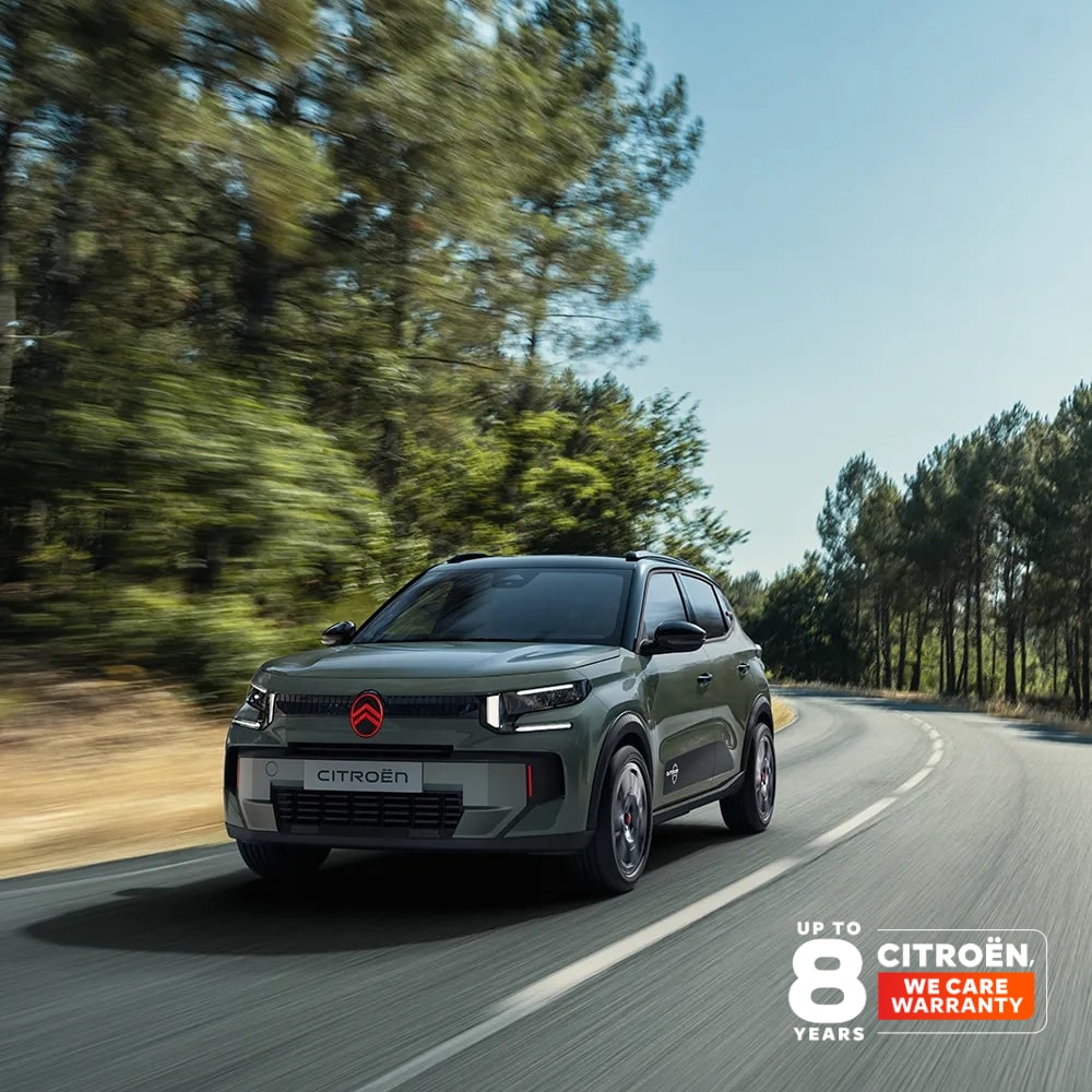 Front-Dreiviertelansicht des Citroën ë-C3 Outdoor mit LED-Lichtsignatur zeigt Citroën Advanced Comfort auf einer Fahrt durch malerische Landschaft