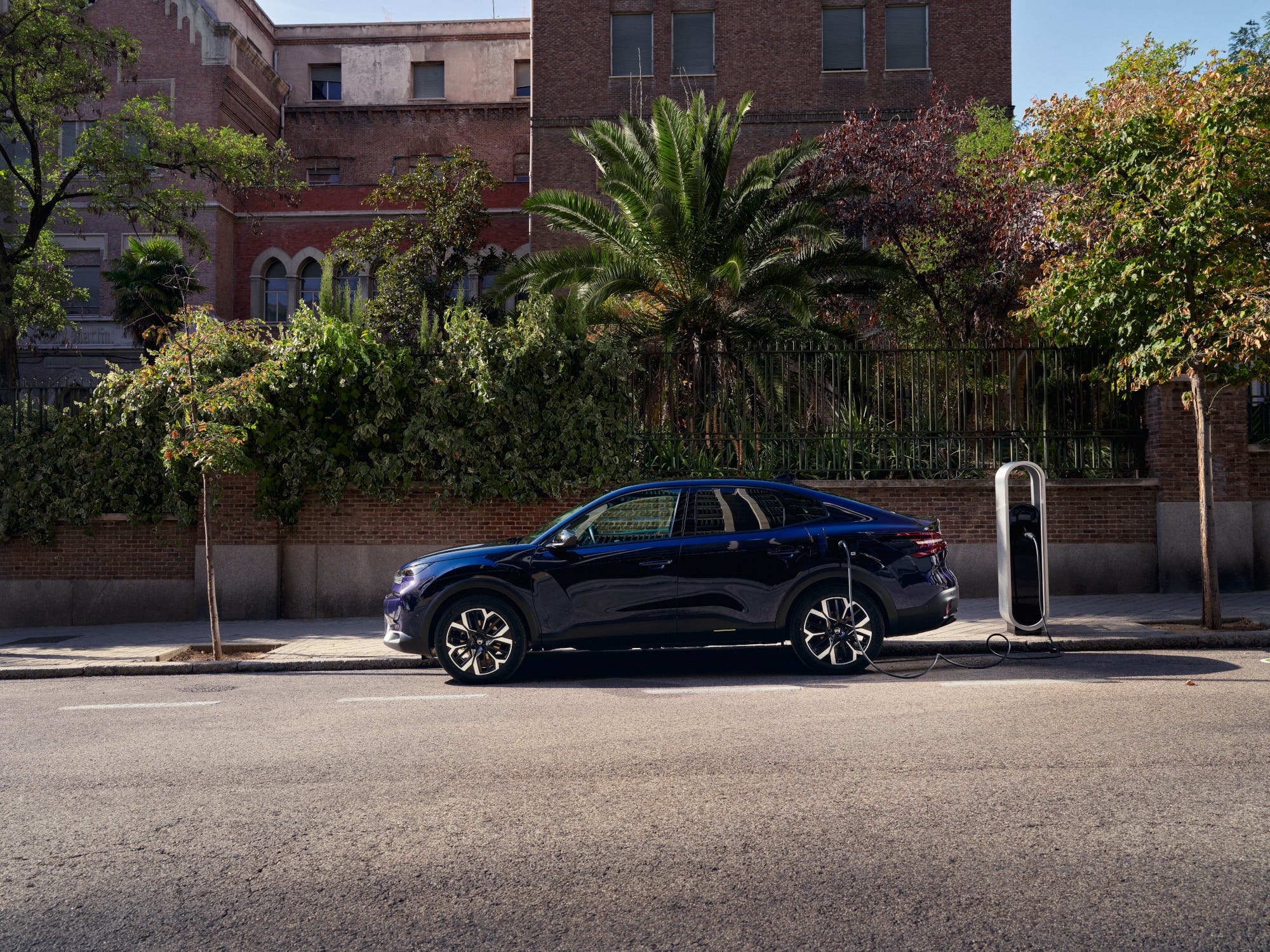 Seitenansicht des elektrischen Citroën C4 X Fastback beim Laden auf der Straße, zeigt bequeme und erschwingliche Stadtmobilität